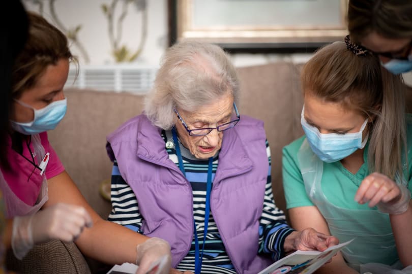 Care home staff reading to female resident