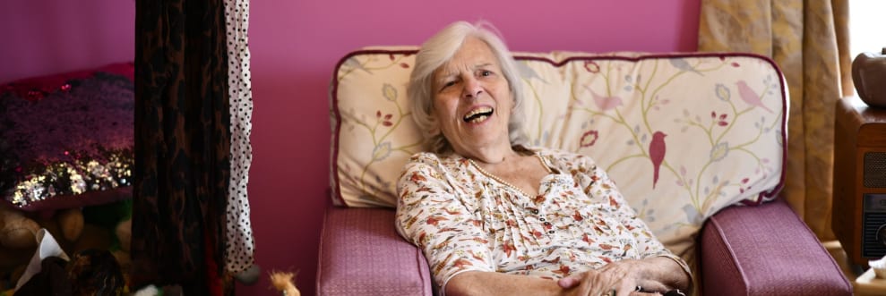 Care home resident sat smiling in a chair
